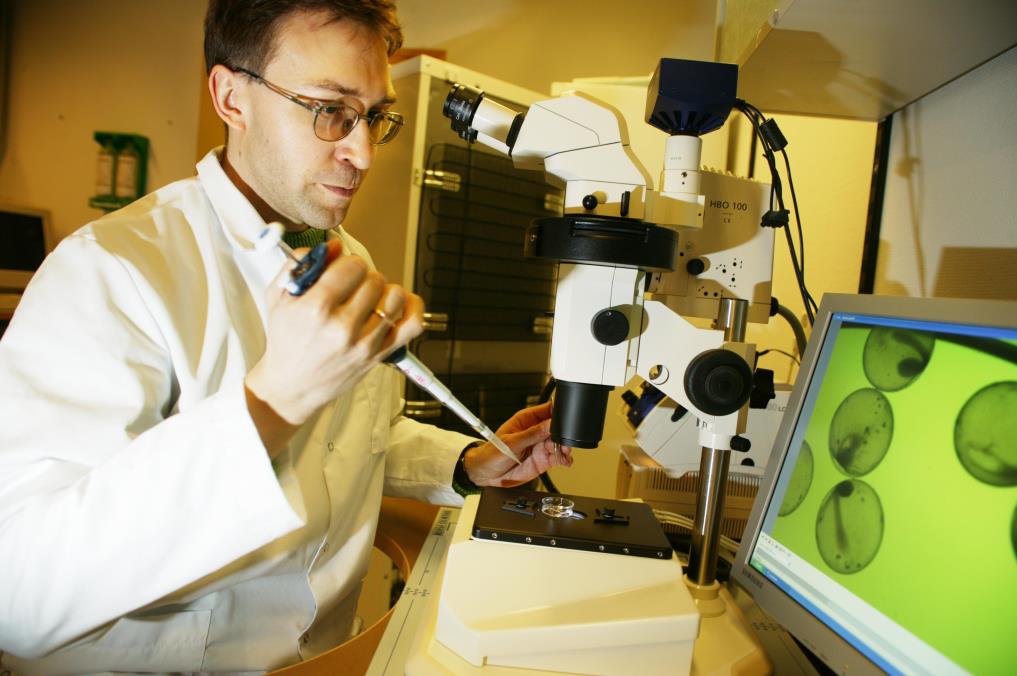 Forsker med pipette og  mikroskop